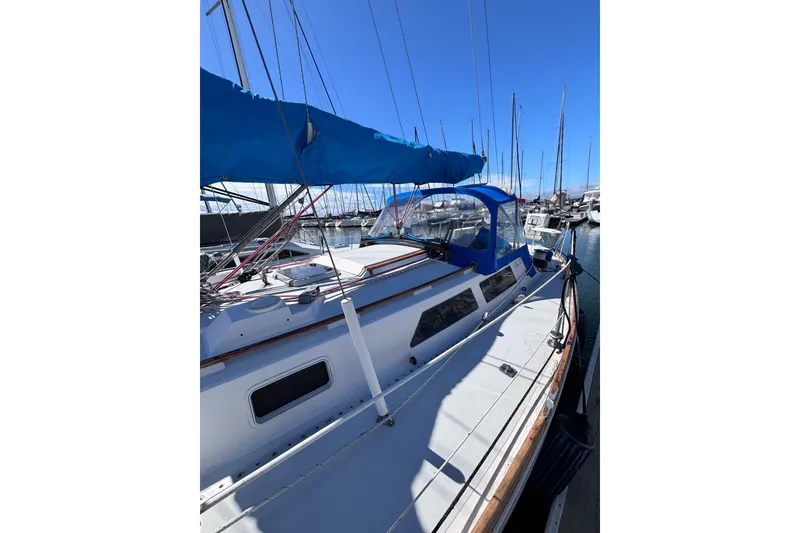 Slide: The Image of 1989 CAL 33 sailboat docked in marina, featuring blue canopy and sleek design. - 4