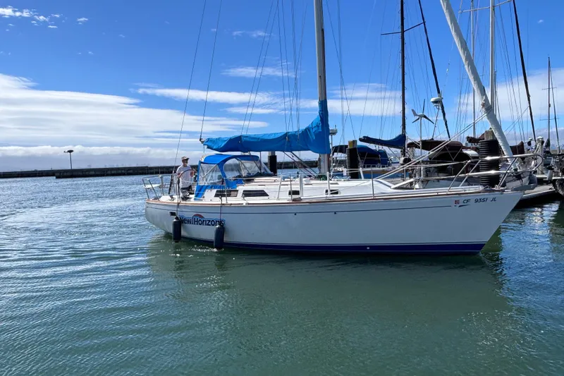 Slide: The Image of 1989 CAL 33 sailboat named "New Horizons" docked in a marina under a clear blue sky. - 1