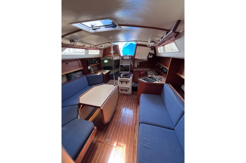 Slide: The Image of Interior of a 1989 CAL 33 sailboat with blue seating and wooden finishes. - 13