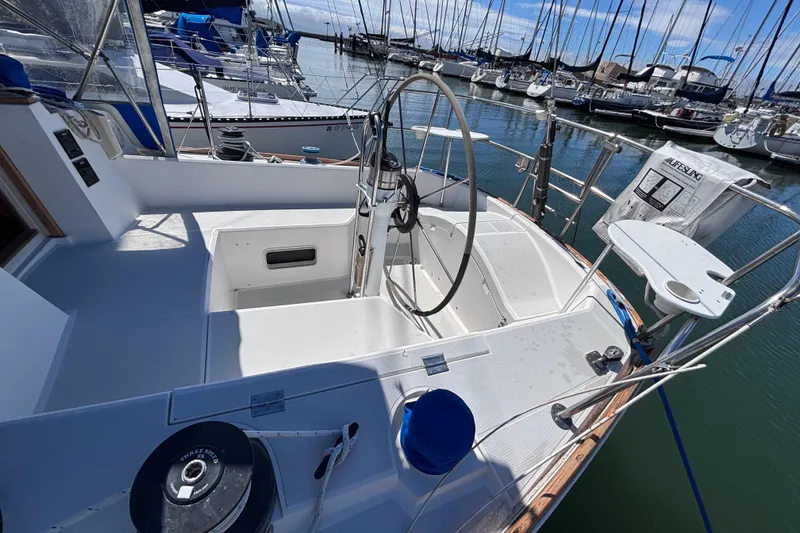 Slide: The Image of Cockpit of a 1989 CAL 33 sailboat docked in a marina, featuring a steering wheel. - 6