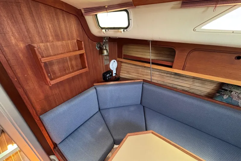 Slide: The Image of Cozy interior of 1989 CAL 33 sailboat with blue cushioned seating and wooden accents. - 16