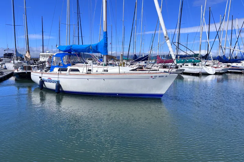 Slide: The Image of 1989 CAL 33 sailboat docked in marina with blue sky and calm water. - 2