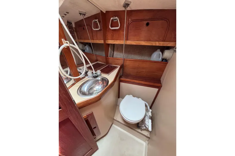 Slide: The Image of Compact 1989 CAL 33 sailboat bathroom with sink, toilet, and wooden cabinetry. - 22