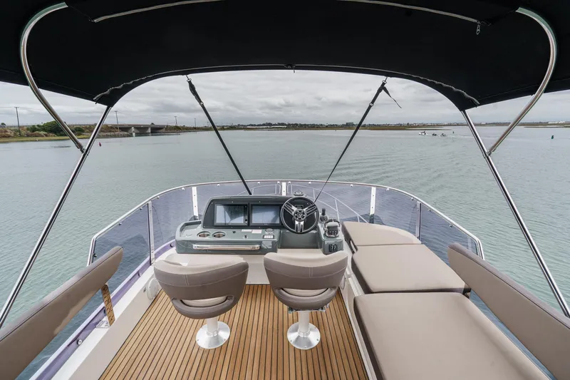 Slide: The Image of Flybridge view of 2017 Bavaria R40 Fly yacht with helm and seating, overlooking calm waters. - 13