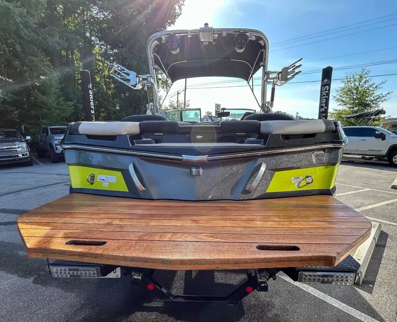 Slide: The Image of Rear view of a 2020 MasterCraft XT23 with a wooden platform, parked in a lot. - 9