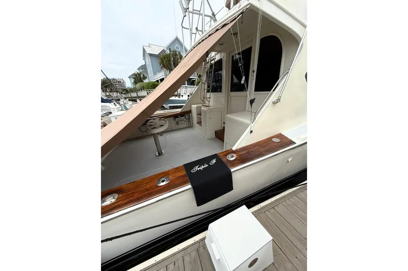 Slide: The Image of 1987 Post 43 Convertible yacht docked, featuring wooden accents and a covered seating area. - 4