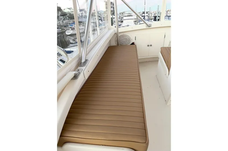Slide: The Image of 1987 Post 43 Convertible boat interior with tan cushioned seating and marina view. - 13