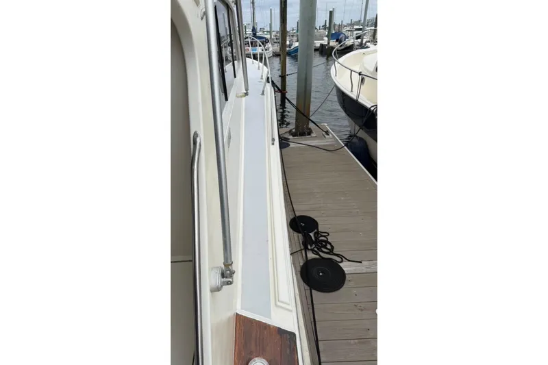 Slide: The Image of 1987 Post 43 Convertible yacht docked at marina, side view with railing and mooring lines. - 9