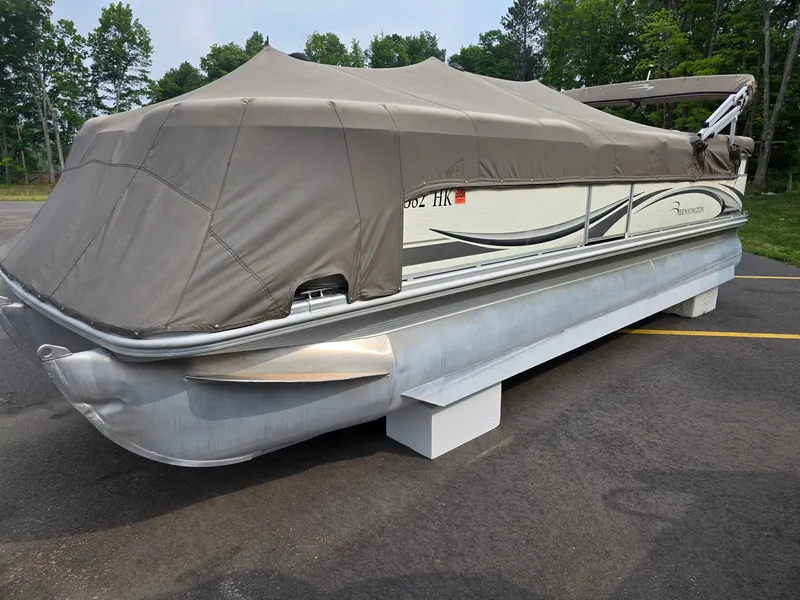 Slide: The Image of A 2008 Bennington 2275RL SPS TRI pontoon boat with a gray cover, parked on a lot. - 2