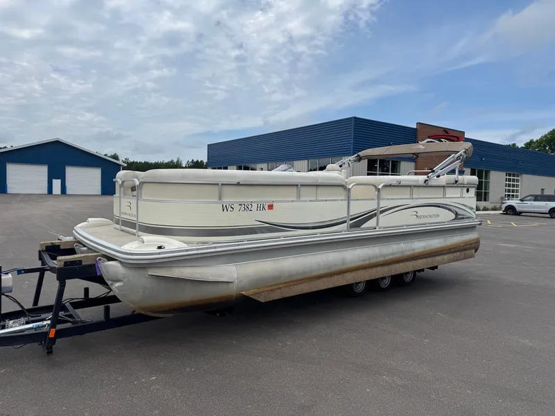 Slide: The Image of 2008 Bennington 2275RL SPS TRI pontoon boat on a trailer, parked in front of a blue building. - 4