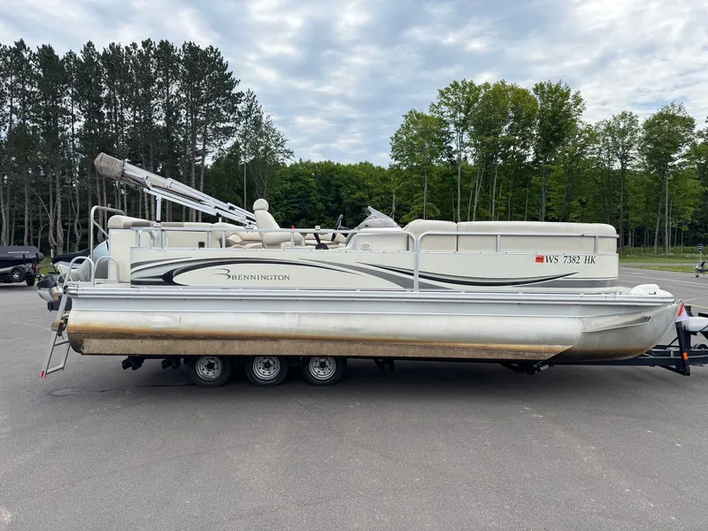 The Image of A 2008 Bennington 2275RL SPS TRI pontoon boat on a trailer, surrounded by trees. - 1