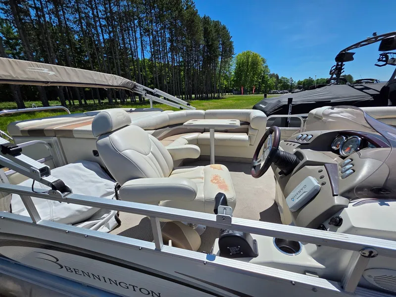 Slide: The Image of The image shows a Bennington pontoon boat with beige leather seats and a helm station. - 3