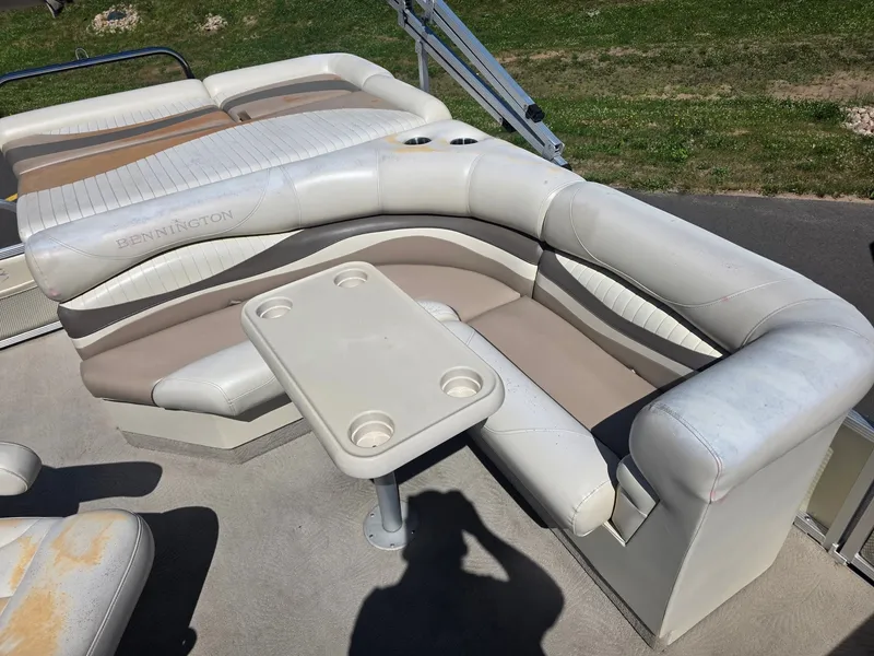 Slide: The Image of A sleek, cream-colored seating area on a Bennington boat with a small table and cup holders. - 14