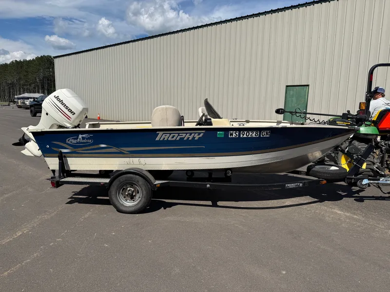 Slide: The Image of A blue and white 2002 Misty Harbor 166C Trophy on a trailer, parked on asphalt. - 2