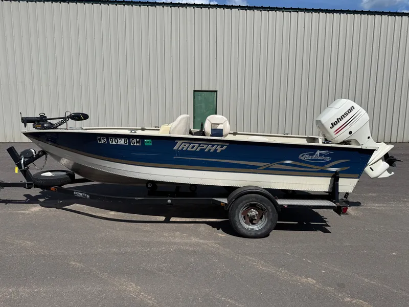 The Image of A blue and white 2002 Misty Harbor 166C Trophy on a trailer in front of a building. - 1