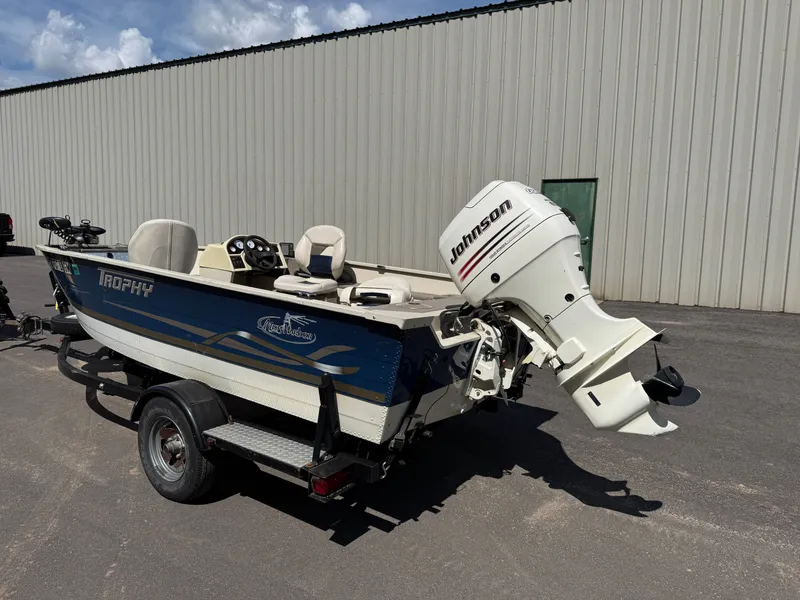 Slide: The Image of A blue and white 2002 Misty Harbor 166C Trophy on a trailer, featuring a Johnson outboard motor. - 3