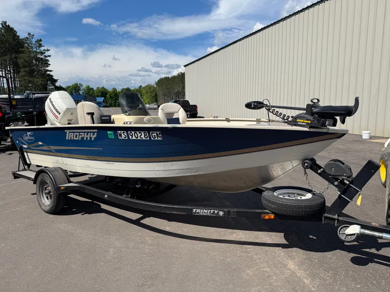 Slide: The Image of A blue and white boat on a trailer, parked in a lot next to a building. - 5