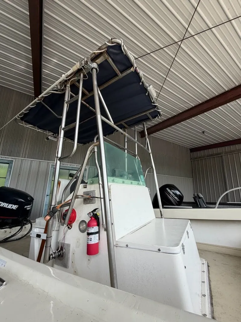 Slide: The Image of A 1974 Aquasport WT20 with a sunshade and helm console in a storage facility. - 10
