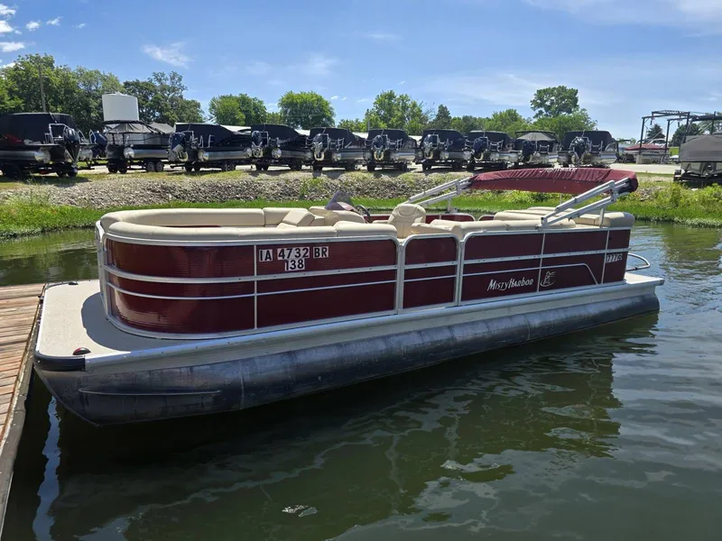 The Image of A red Misty Harbor 245CR pontoon boat is docked on the water. - 1