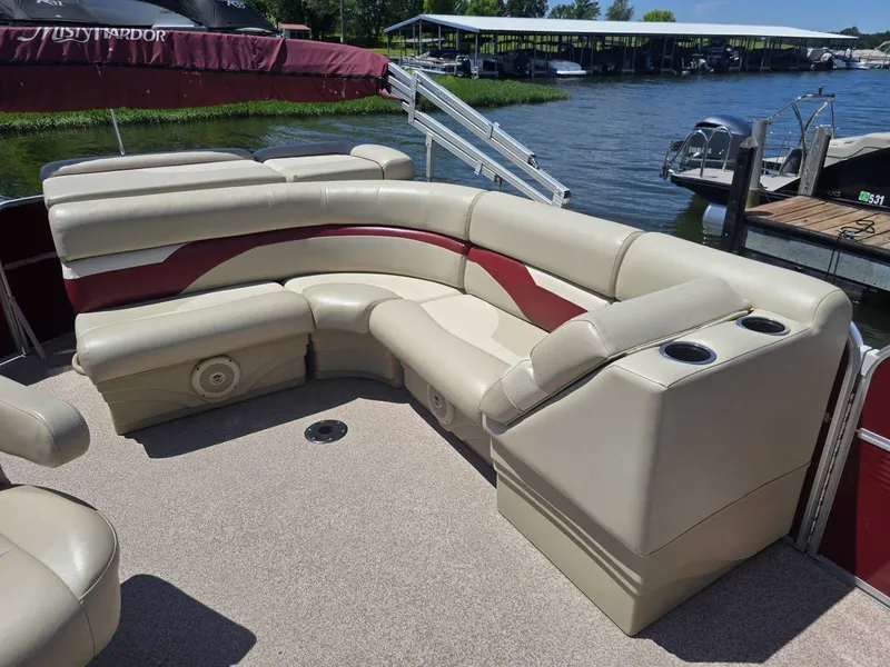 Slide: The Image of The image shows the interior of a 2016 Misty Harbor 245CR pontoon boat with beige and red seating. - 6