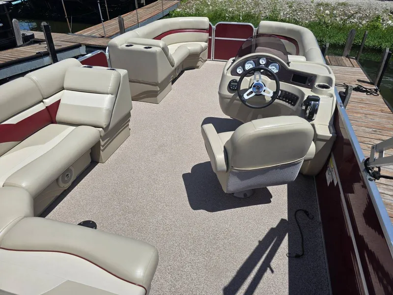 Slide: The Image of The image shows the interior of a 2016 Misty Harbor 245CR pontoon boat with beige seating. - 12