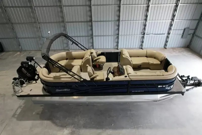 Slide: The Image of A 2019 Silver Wave 230 Island CLS pontoon boat in a warehouse, featuring beige seating and black railing. - 3