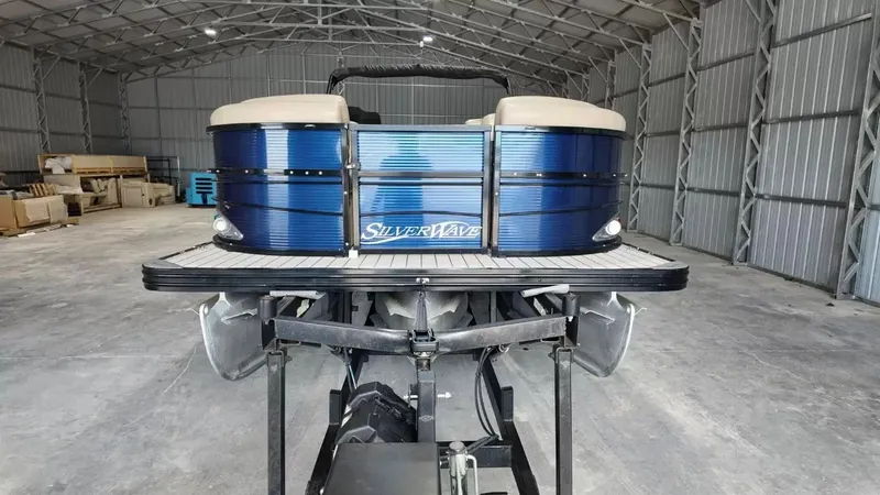 Slide: The Image of A 2019 Silver Wave 230 Island CLS pontoon boat in a warehouse, featuring blue exterior paneling. - 16