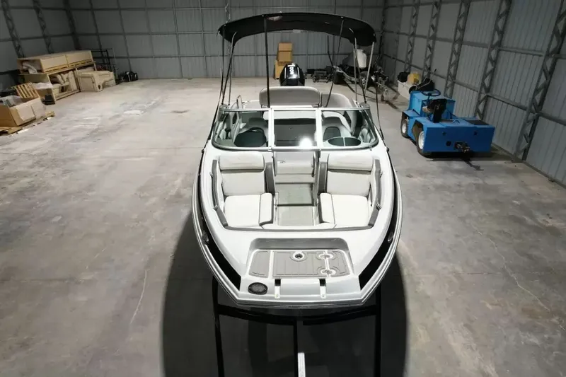 Slide: The Image of 2021 Crownline Eclipse E215 XS in a warehouse, featuring a Bimini top and spacious cockpit. - 17