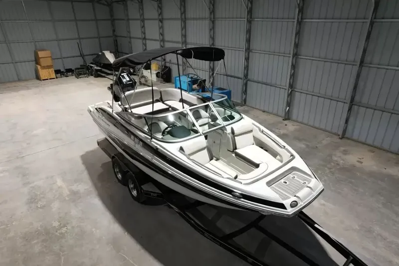 Slide: The Image of A 2021 Crownline Eclipse E215 XS boat is in a warehouse on a trailer. - 19