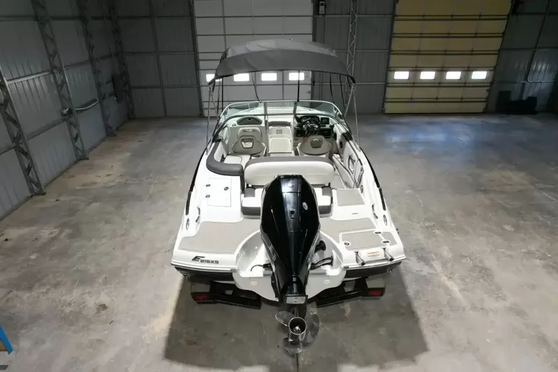 Slide: The Image of A 2021 Crownline Eclipse E215 XS boat in a warehouse, featuring a black outboard motor. - 8