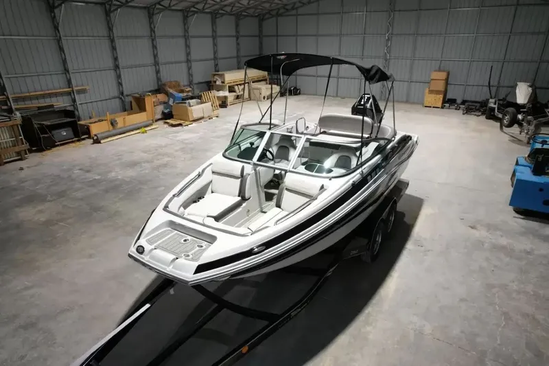 Slide: The Image of A 2021 Crownline Eclipse E215 XS boat is on a trailer in a warehouse. - 12