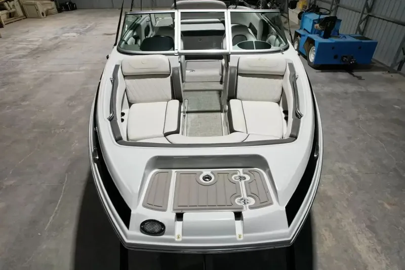Slide: The Image of A 2021 Crownline Eclipse E215 XS boat with white and gray interior, situated in a warehouse. - 14