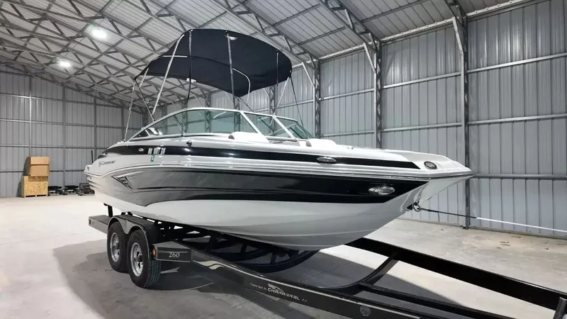 Slide: The Image of A 2021 Crownline Eclipse E215 XS boat on a trailer inside a warehouse. - 18