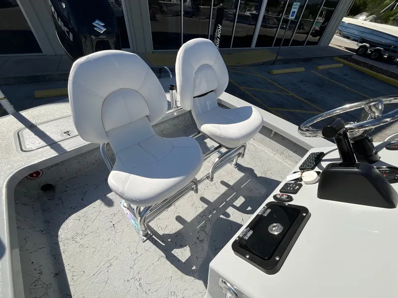 Slide: The Image of Two white seats on a boat with a gray floor and steering console. - 11