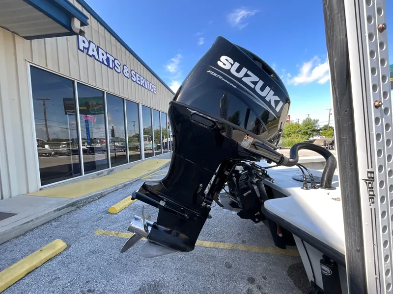 Slide: The Image of A Suzuki outboard motor is attached to a boat parked outside a parts and service shop. - 4