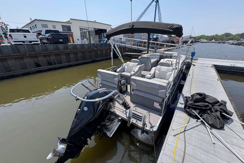 Slide: The Image of 2023 Crest Classic DLX 220 pontoon boat docked at marina, featuring spacious seating. - 11