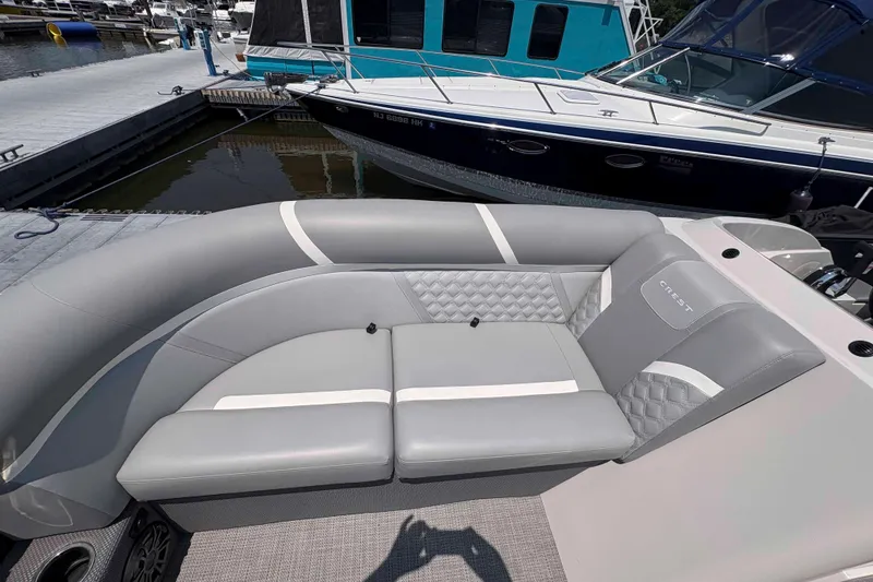 Slide: The Image of 2023 Crest Classic DLX 220 boat with luxurious gray seating at a marina. - 7