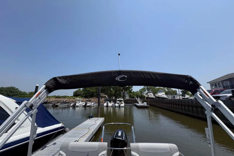 Slide: The Image of 2023 Crest Classic DLX 220 boat docked at a marina under clear blue skies. - 21