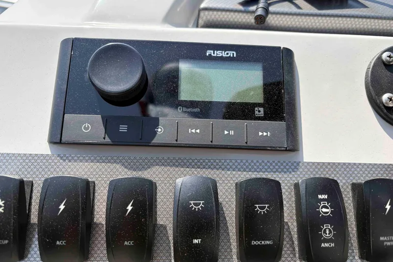 Slide: The Image of Control panel of 2023 Crest Classic DLX 220 with Fusion audio system and switches. - 24
