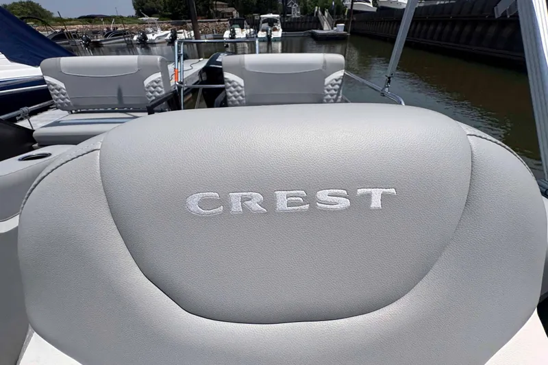 Slide: The Image of 2023 Crest Classic DLX 220 boat interior with branded seating at a marina. - 20