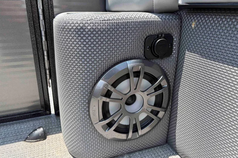 Slide: The Image of 2023 Crest Classic DLX 220 boat speaker and power outlet on woven upholstery. - 25