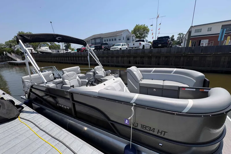 The Image of 2023 Crest Classic DLX 220 pontoon boat docked at marina under clear blue sky. - 0