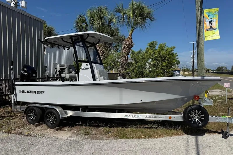 The Image of 2027 Blazer Bay 2440 boat on trailer, parked outdoors under clear blue sky. - 1