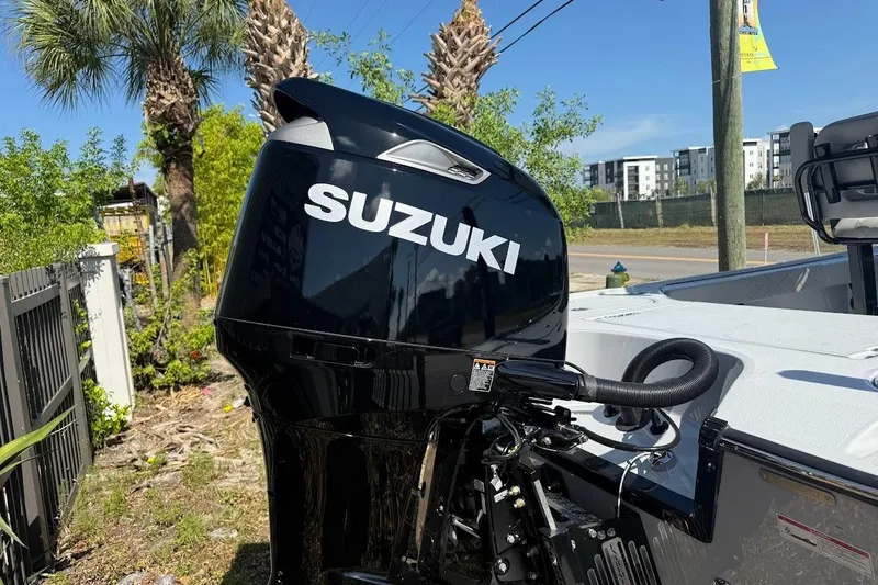 Slide: The Image of 2027 Blazer Bay 2440 boat with Suzuki outboard motor, parked near palm trees. - 10
