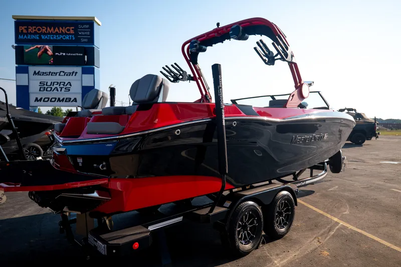 Slide: The Image of 2027 MasterCraft XT24 boat in red and black on trailer at marine dealership. - 11