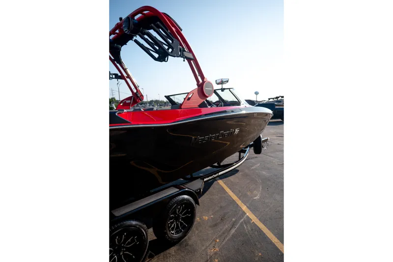 Slide: The Image of 2027 MasterCraft XT24 boat with red accents on a trailer in a parking lot. - 13