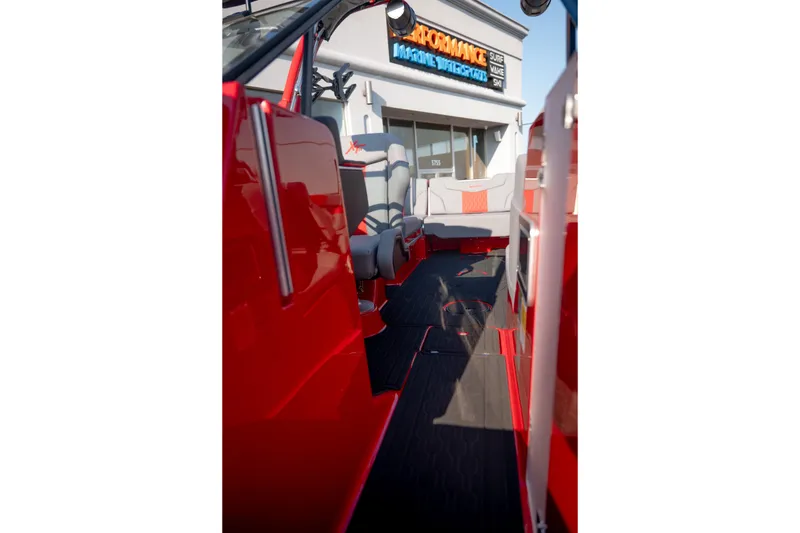 Slide: The Image of 2027 MasterCraft XT24 boat interior with red and gray seating, outside a marine store. - 19