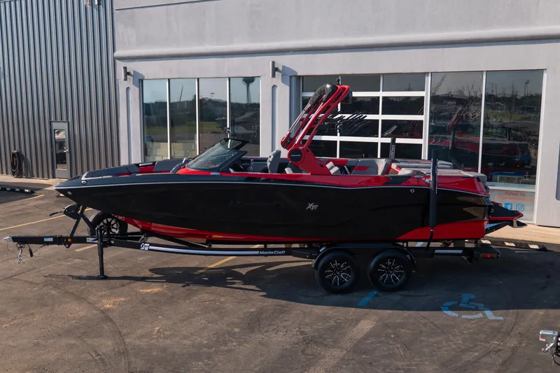 Slide: The Image of 2027 MasterCraft XT24 boat in black and red on a trailer outside a building. - 3