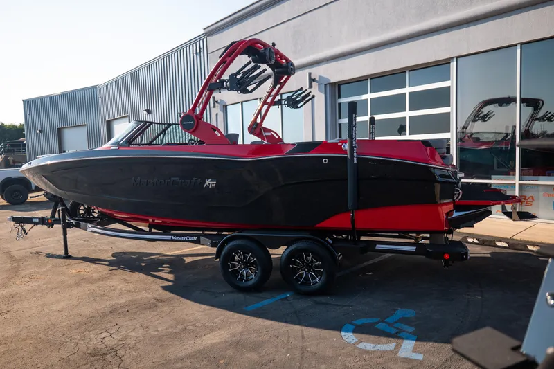 Slide: The Image of 2027 MasterCraft XT24 boat in black and red on a trailer outside a building. - 5