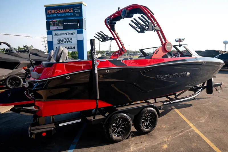 Slide: The Image of 2027 MasterCraft XT24 boat in black and red on a trailer at a dealership. - 12